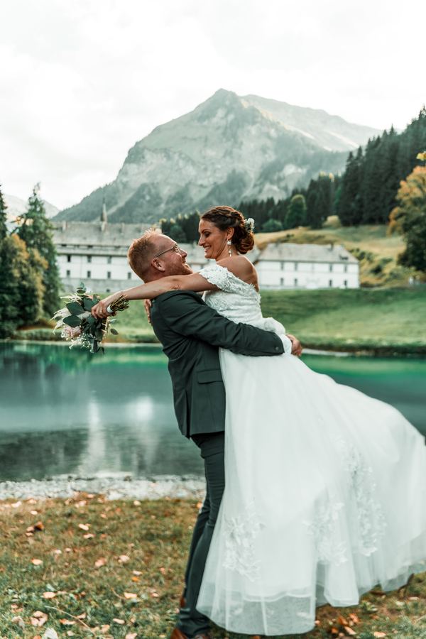 Le marié soulève la mariée devant le lac