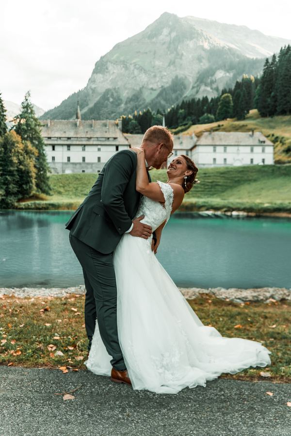 Les mariés enlacés devant le lac de montagne